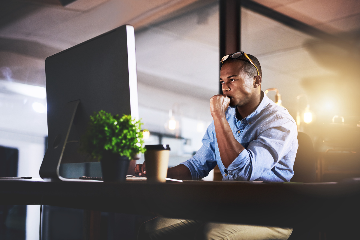 a man sits at his computer staring intently at the monitor in a deep state of focus