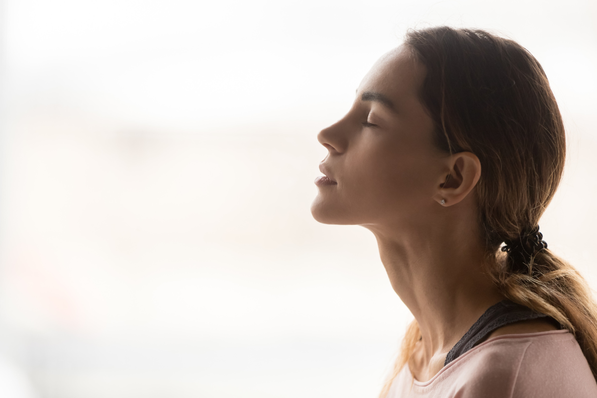 side profile view of woman breathing set against a stark white background