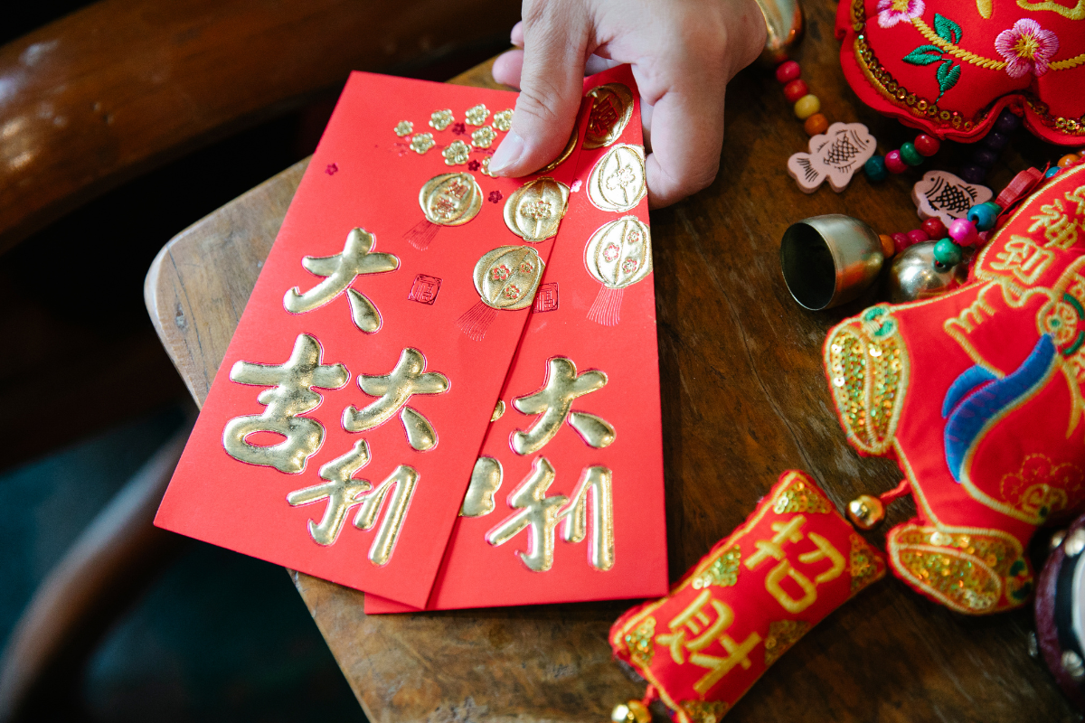 someone is handing a bright red money envelope with beautiful gold accents to someone off camera