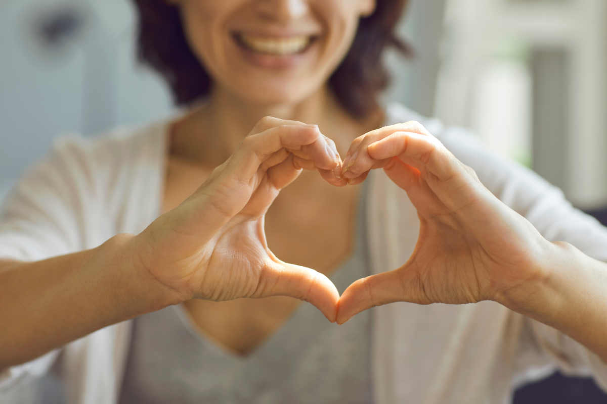 a woman makes a heart symbol with her hands