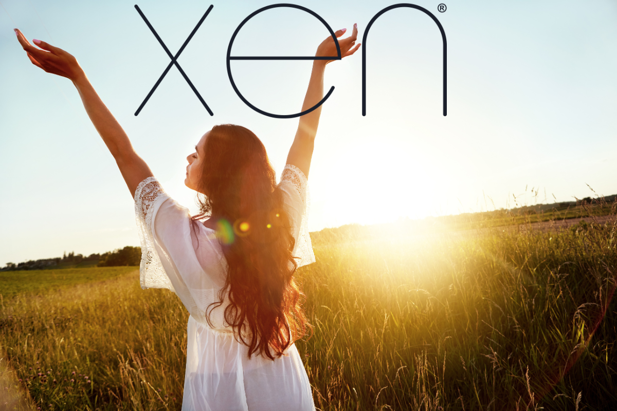 woman with hands up towards the sky with the sun setting