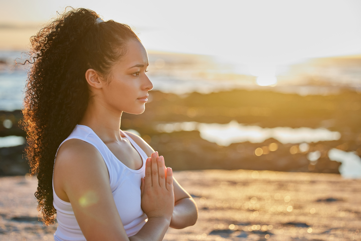 a woman meditates in front of the ocean