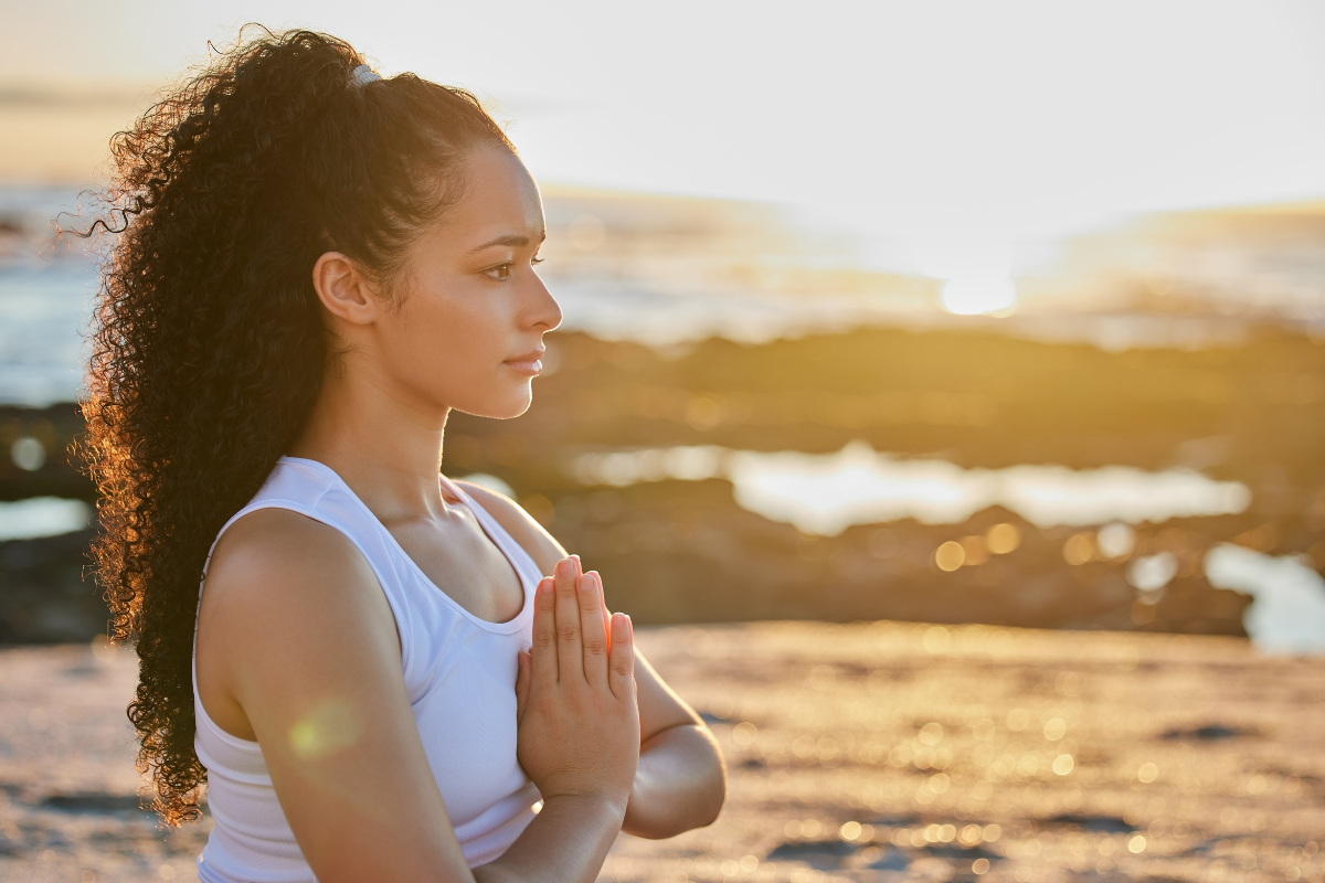 a woman meditates in front of the ocean 