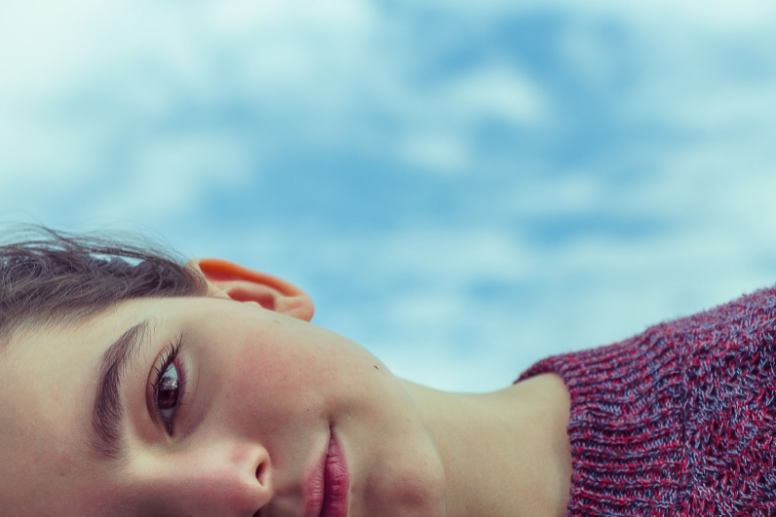 woman laying outside with sky and clouds in background
