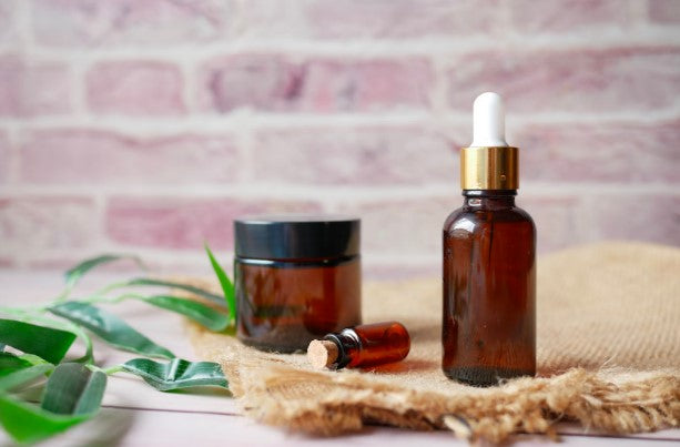 brown containers full of essential oils rest on a white surface with a brick background