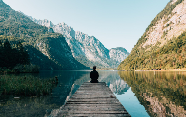 Guy sitting at end of bridge looking over river