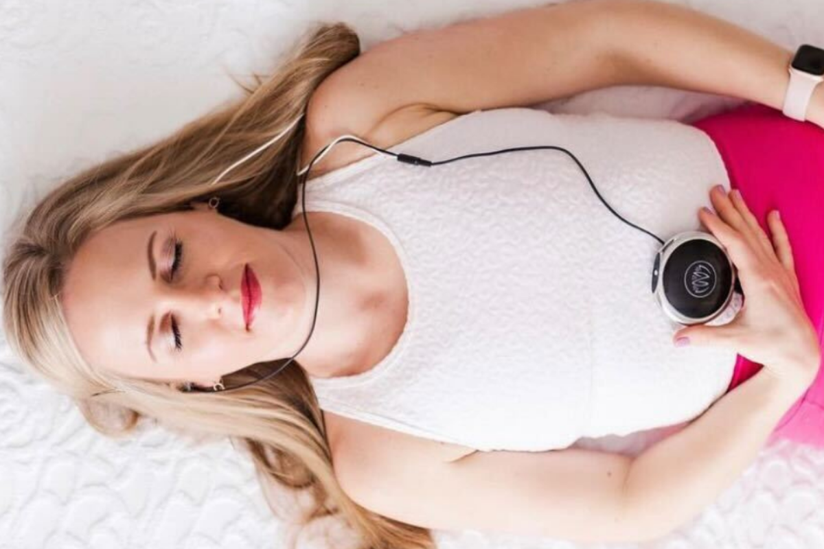 A woman laying on the bed with her Neuvana device