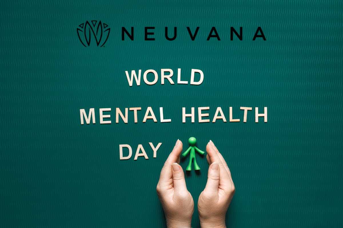 Hands holding a small green figure against a teal textured background. Above the hands, the words 'World Mental Health Day' are arranged in wooden letters