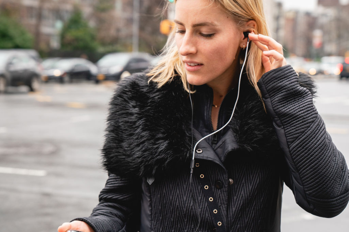 woman wearing a coat during the winter season with neuvana headphone in her ear