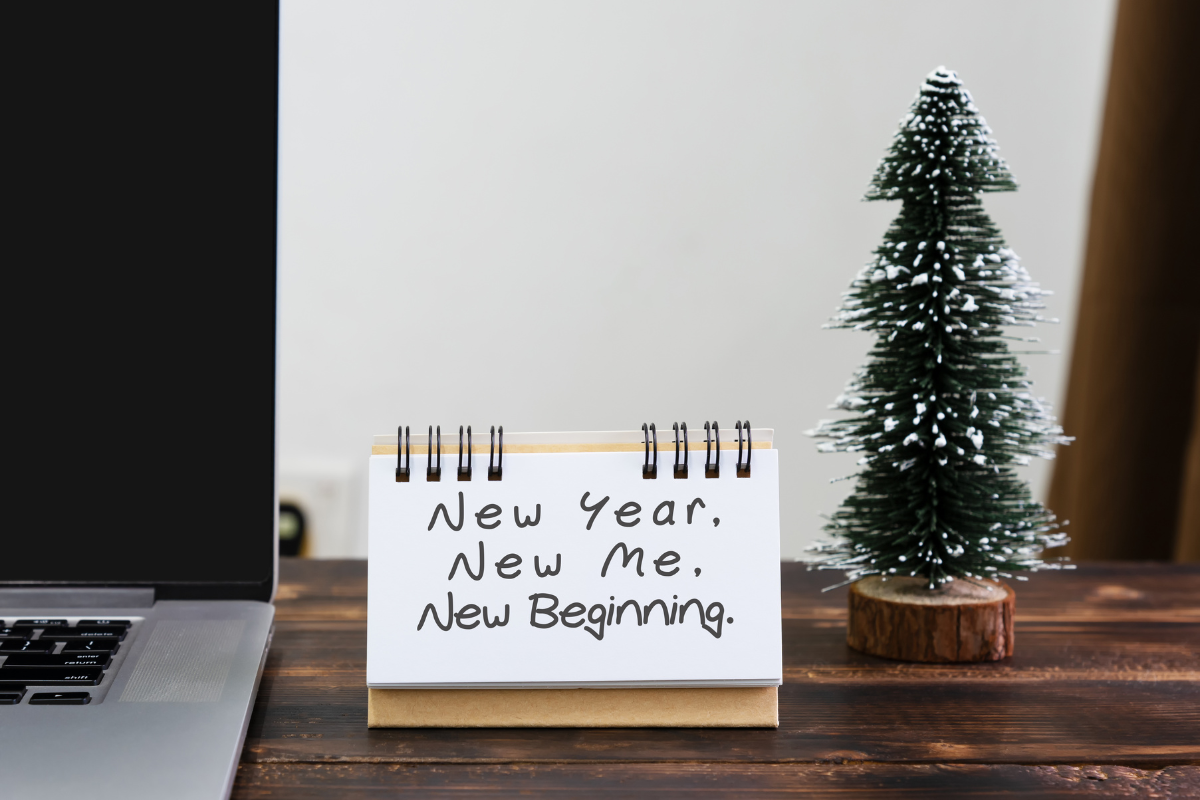 a desk calendar sits next to a small tree figurine and the message says "new year, new me, new beginning"