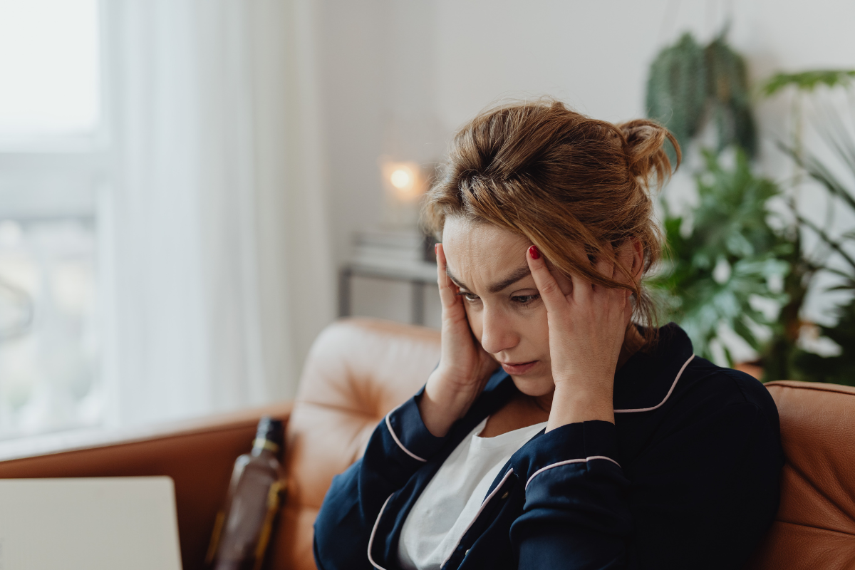 a woman sits with her hands to her head looking clearly stressed out