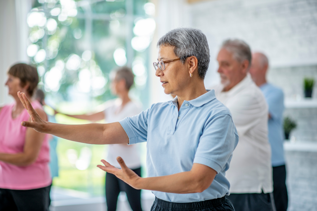 a group of older folks are taking a tai chi class