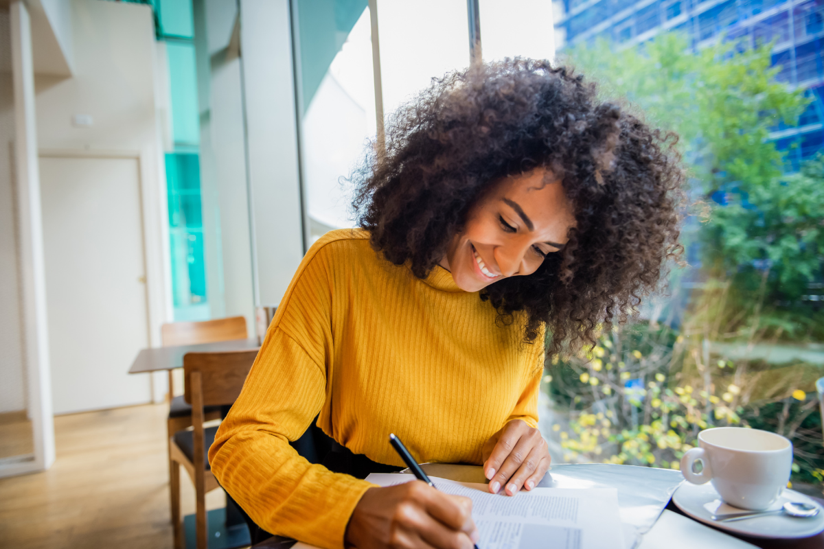 a young woman with pretty curly hair sits at a table studying