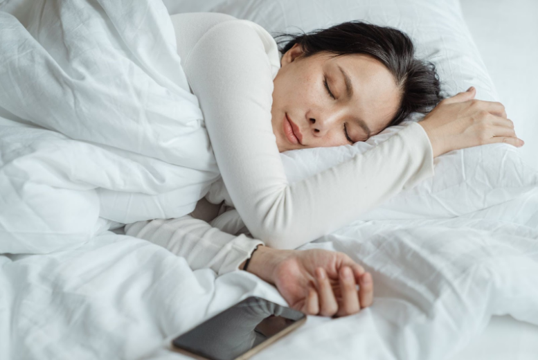 woman sleeping next to her phone in bed