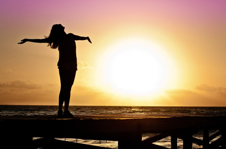 woman rejoicing at the beach sunset